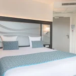 Chambre Double Supérieure à l’Hôtel Versailles Chantiers avec grand lit double et tête de lit design