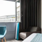 Chambre Triple Supérieure à l’Hôtel Versailles Chantiers avec espace salon et vue extérieure